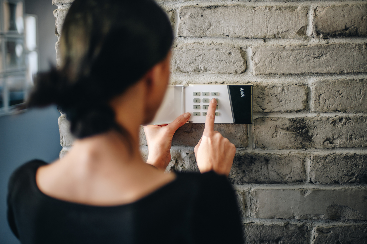 Young woman entering security pin on home alarm keypad. Young woman entering security pin on home alarm keypad. Home security system